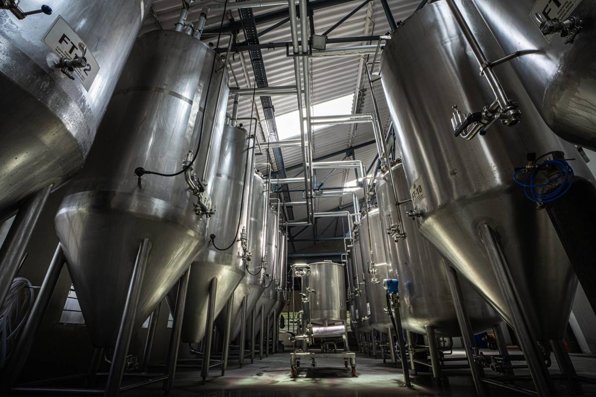 Low-angle view down a corridor of stainless fermentation tanks